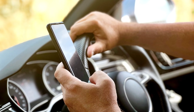 man holding phone whilst driving